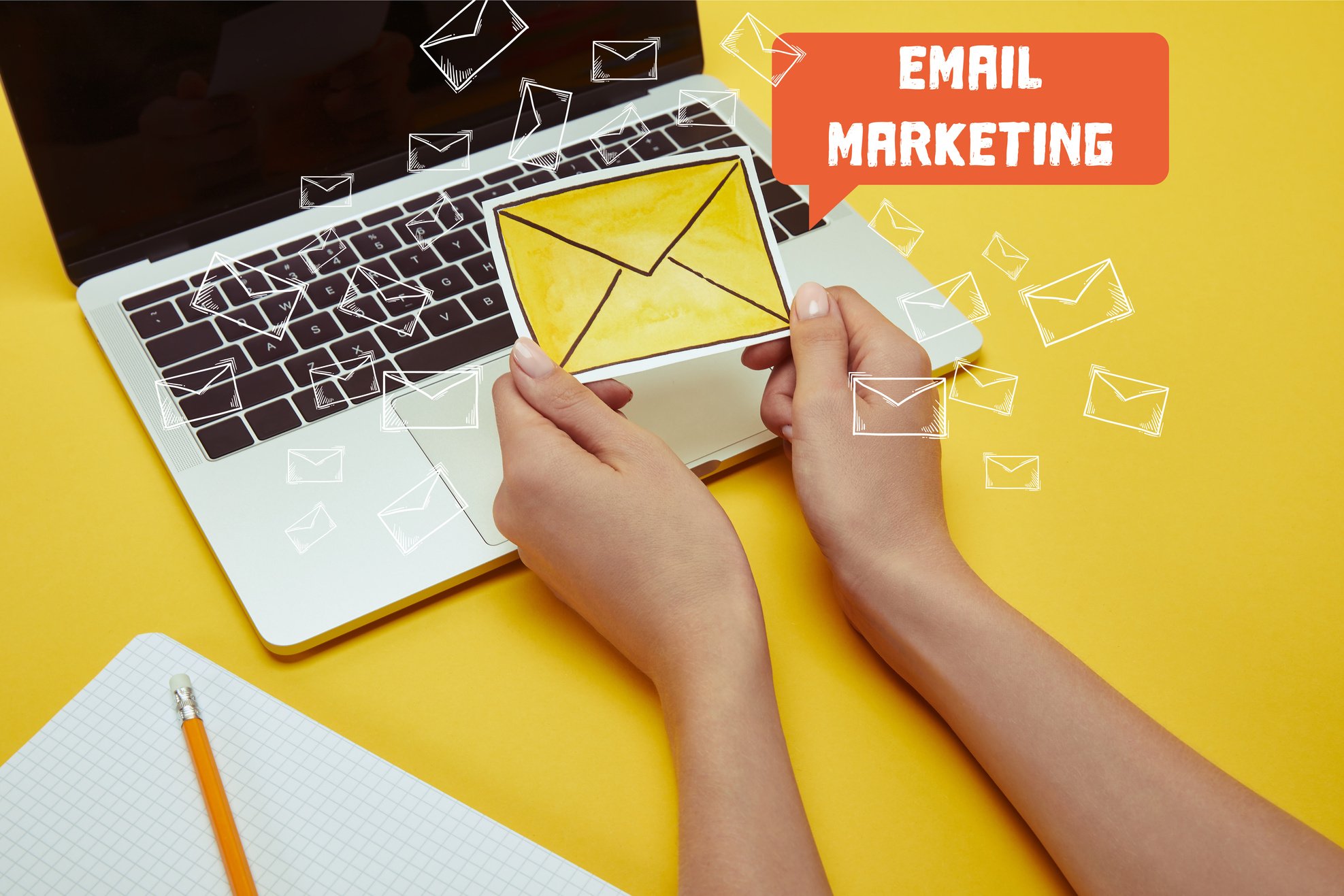 cropped image of woman holding envelope sign near laptop with 'email marketing' lettering and email icons